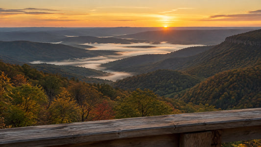 Sunrise over layered Appalachian ridges with mist pooling in the valley below, seen from a wooden deck railing